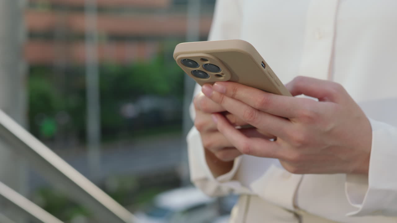 Close-up of a person holding and using a smartphone outdoors