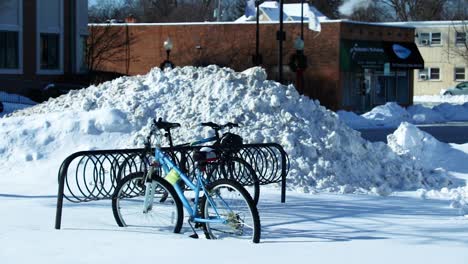 a couple bycicles tied to a bike rack seem to be frozen to the ground