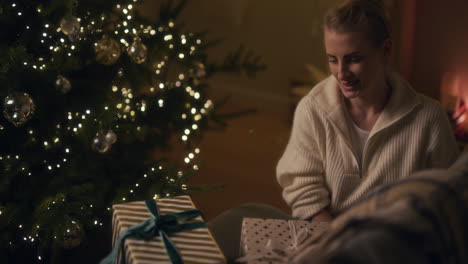 a woman prepares christmas presents under the christmas tree