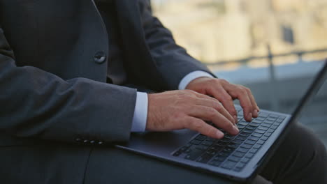 manager hands typing keyboard closeup. urban businessman in suit work laptop
