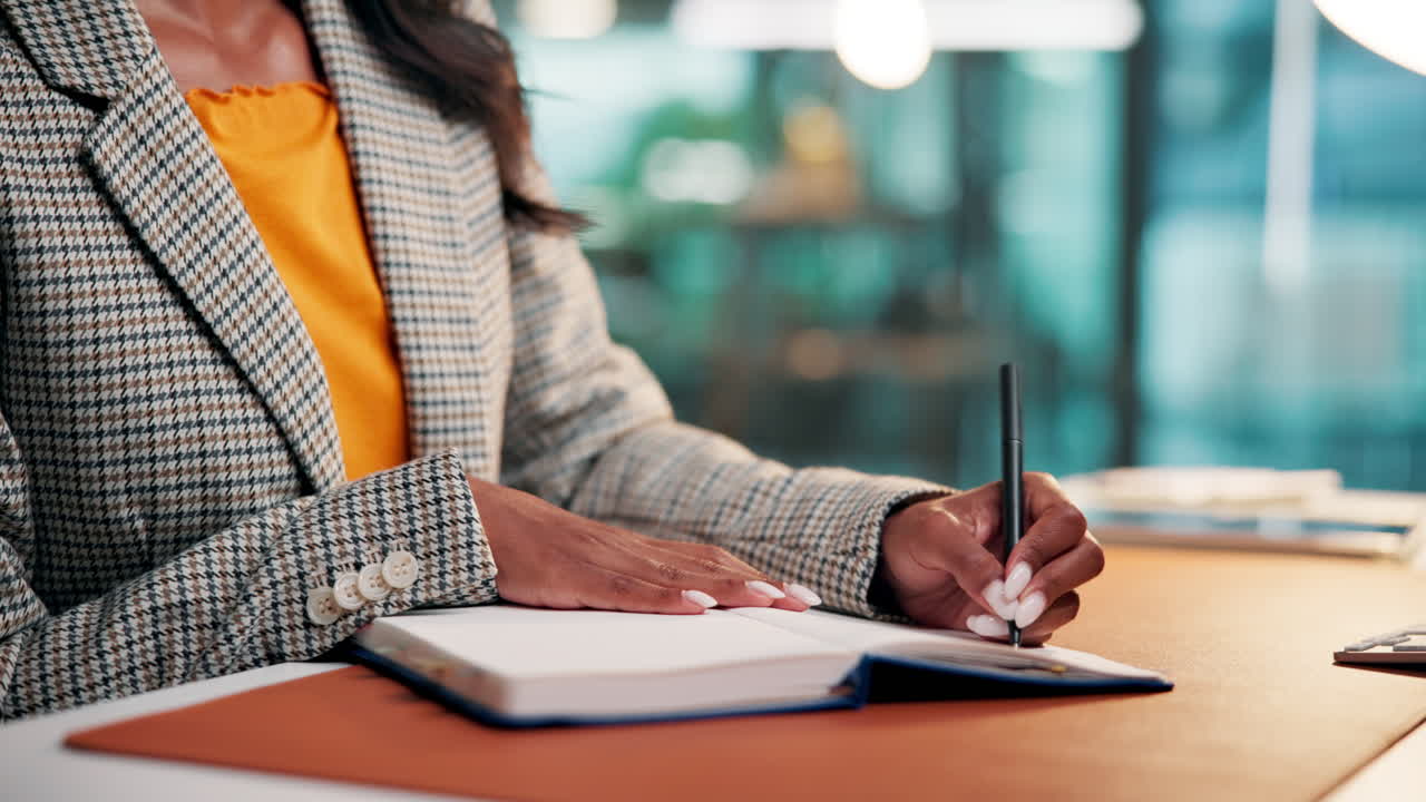 Professional Woman Writing Notes in a Notebook at Her Desk