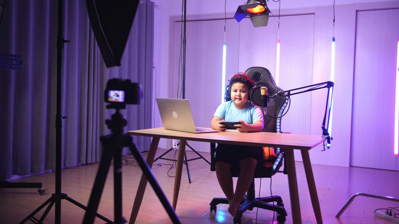 Asian Little Boy Holding Mobile Phone With Mock Up Green Screen And Talking While Live Stream, Professional Light Equipment