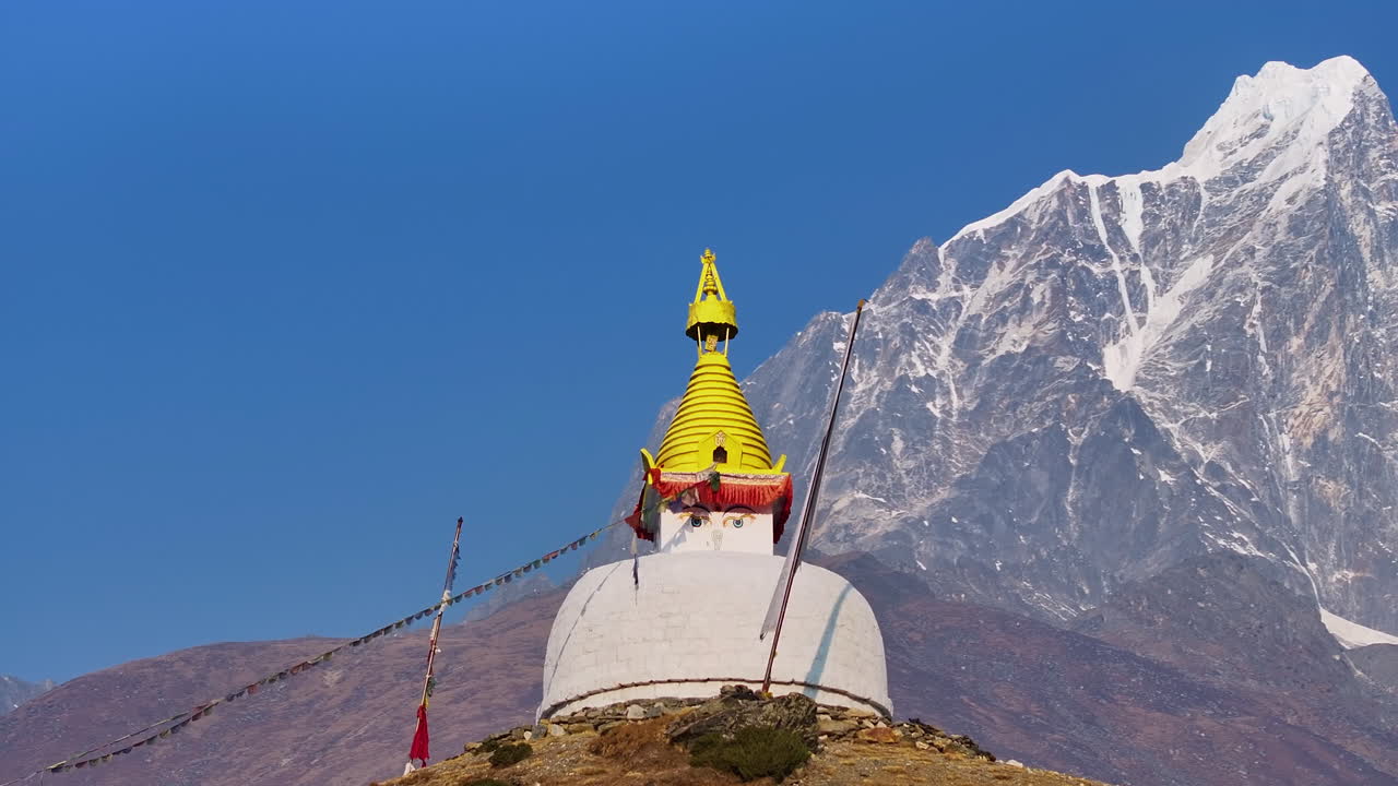 Close-up drone shot of a Buddhist stupa in Dingboche, Khumbu, Nepal. Mt. Cholatse shines in the backdrop, creating a peaceful and spiritual Himalayan scene on Everest Base Camp trekking route