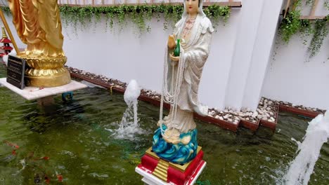 a school of colorful koi fish swimming by the water surface in a fish pond and a statue in bangkok, thailand- closeup shot