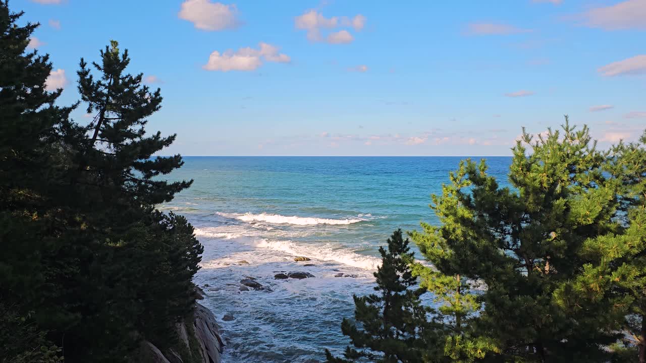 Panoramic zoom out of surrounding cliffs and ocean waves in South Korea, showcasing a scenic peaceful retreat