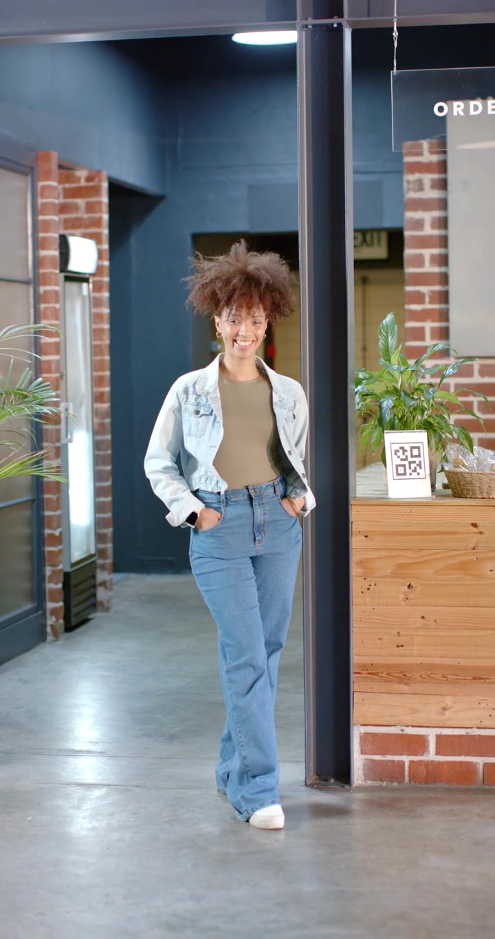 Vertical video: African American woman walking from dim hall into cafe to QR-code counter to scan