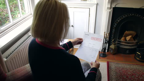 una anciana irreconocible preocupada por las deudas abriendo una carta de deuda