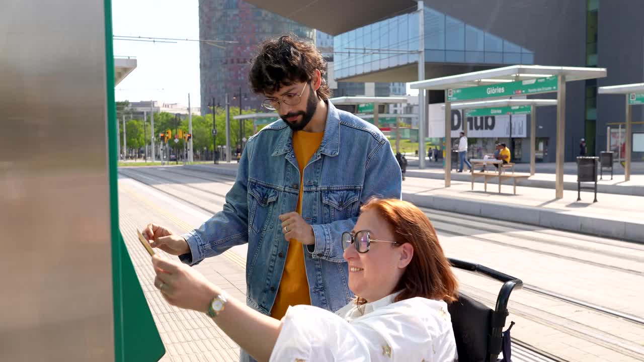 A man assisting a woman in a wheelchair at a tram stop