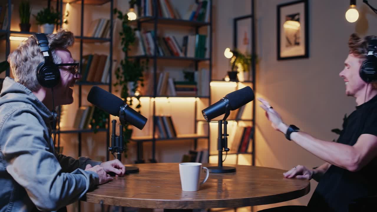 Two people recording a podcast video, sitting at a round table with microphones
