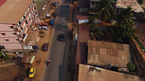 Aerial-view-following-cars-on-the-suburban-streets-of-Yaounde,-golden-hour-in-Cameroon
