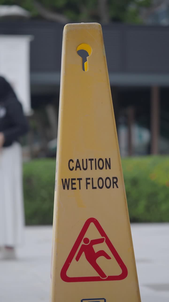 Yellow Caution Wet Floor Sign with Person Walking in Background