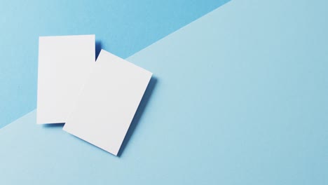 blank white business cards on blue background, copy space, slow motion