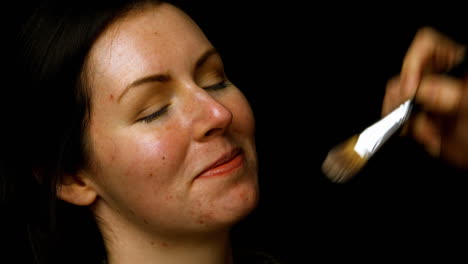 hand applying makeup to woman