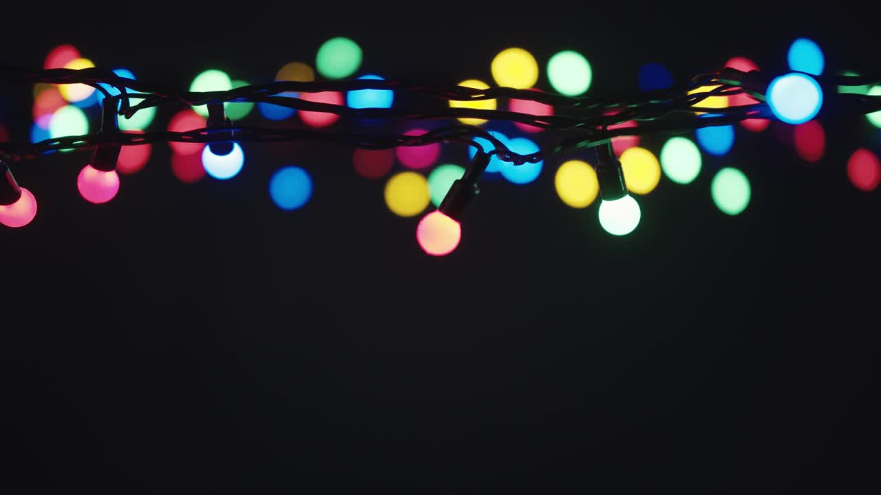 refocusing. luces de guirnaldas parpadeando lentamente en el fondo oscuro con lugar para el texto.