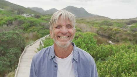 portrait of smiling senior caucasian man standing on path