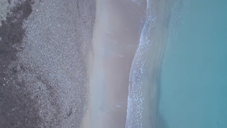 Top-down-view-of-waves-splashing-on-the-sandy-beach