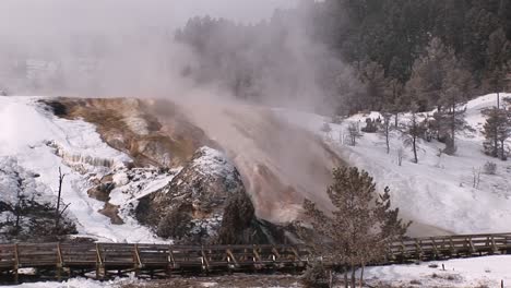 mist rises from yellowstone national park's hot springs' terraces in winter