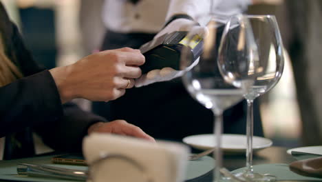 female hand paying by bank card in restaurant. contactless payment