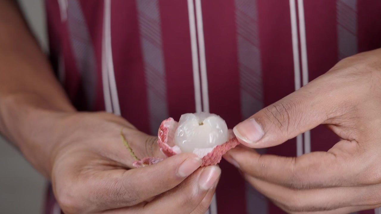 Persona che sbuccia un litchi fresco