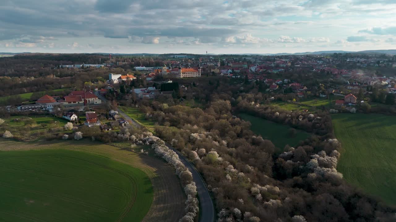 volando hacia la ciudad bohemia kostelec nad černými lesy con campos y árboles en flor en el frente