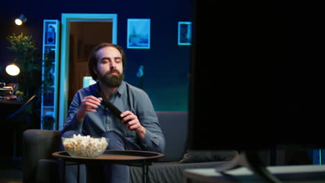 man arriving home, relaxing on couch while watching movies on tv