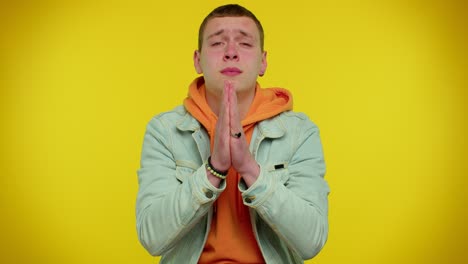 hombre adolescente elegante orando, mirando hacia arriba y haciendo un deseo, pidiendo ayuda a dios, pidiendo disculpas