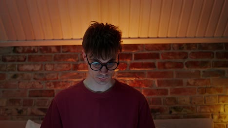 young man working on a laptop in a bedroom at night