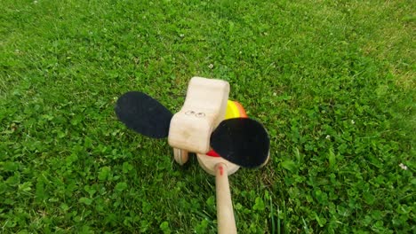 wooden toy puppy with wheels rides through the grass