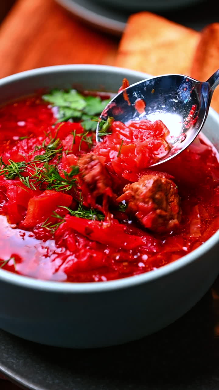 Spoon lifting beet soup serving. Beet soup with lifted spoon showing hearty texture and fresh dill