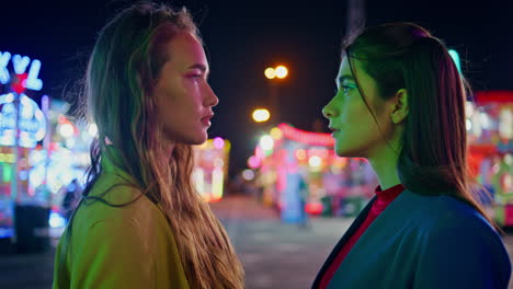 two girlfriends looking eyes each other closeup. female couple meeting luna park
