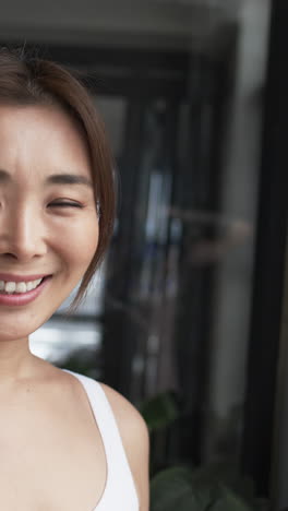 vertical video: smiling woman in white top posing indoors, looking confident and happy