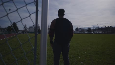 male walking near fence and looking around - strong athletic muscular black man fitness outdoor training preparation in 4k