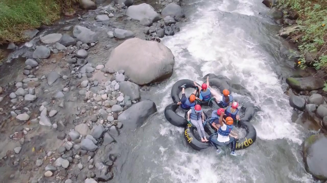 Orang-orang bersenang-senang melakukan tubing di sungai Mindo dengan perlengkapan keselamatan.
