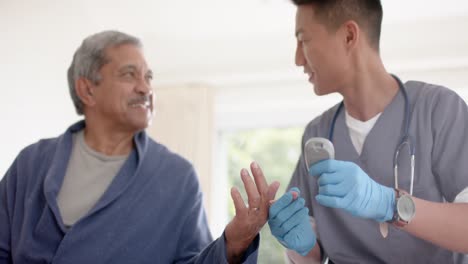 diverso médico masculino examinando la sangre de un paciente masculino anciano en casa, cámara lenta