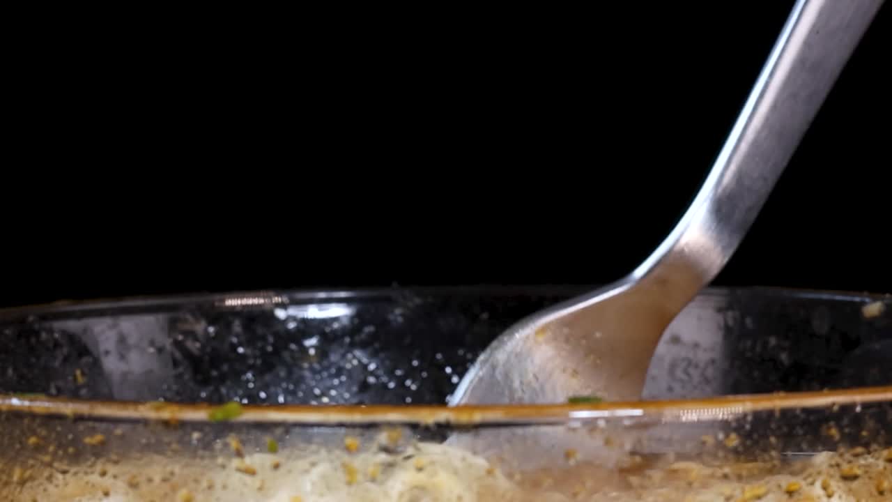 A metal fork lifts and twirls yellow instant noodles from a clear glass bowl