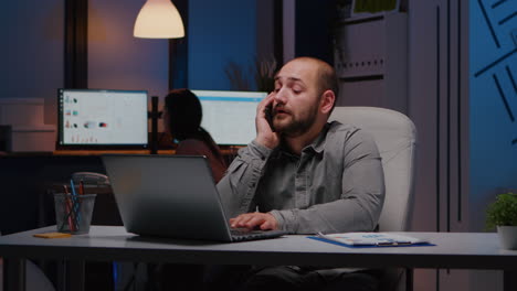 Exhausted-businessman-sitting-at-desk-table-discussing-management-ideas