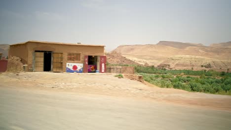Driving-through-a-desert-Moroccan-Village-on-a-very-hot-sunny-day,-looking-outside-the-car-window