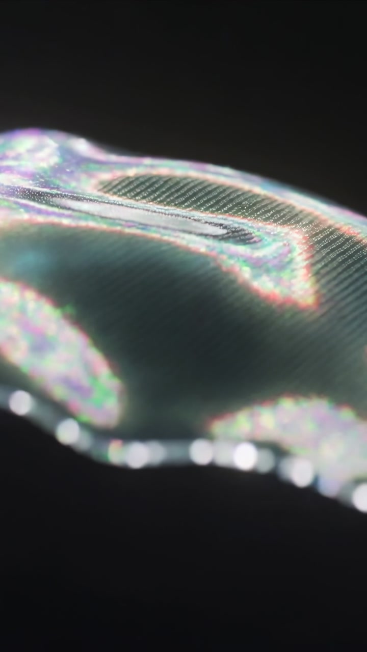 Vertical video: Lighting shift making thin film moving across dark backdrop, showing bokeh mesh