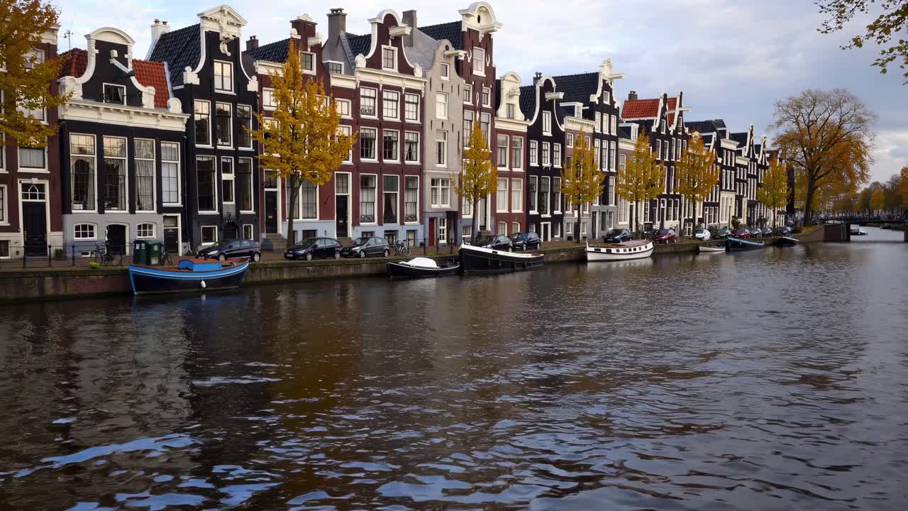 Scenic view of historic canal houses along a tranquil waterway, showcasing vibrant autumn foliage and reflections, capturing the essence of serene urban life in a picturesque setting