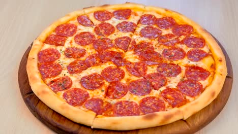 slicing salami pizza on wooden board on the table. close-up side view.