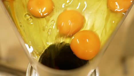 close up of egg yolks falling down into a pipe in a noodle or cake factory