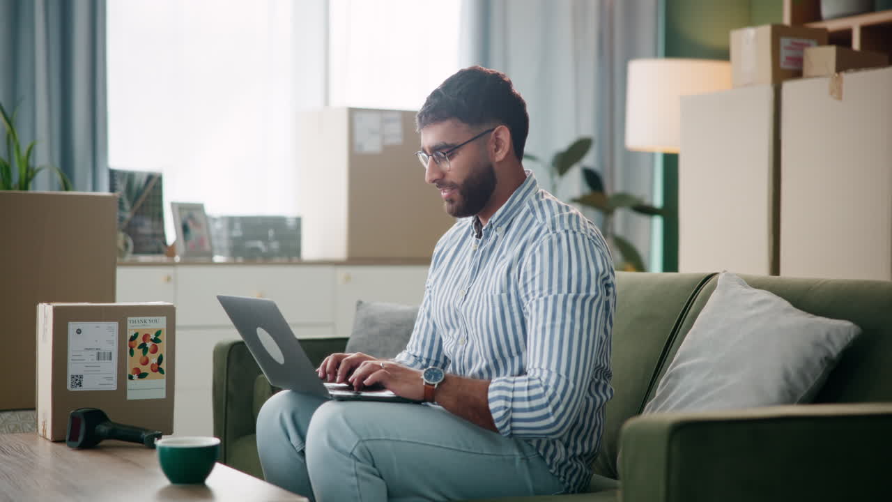 Man working on laptop in new apartment with moving boxes