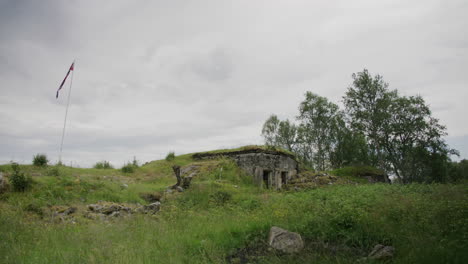 Coastal-bunker-with-Norwegian-pennant-in-static-shot,-cloudy-sky