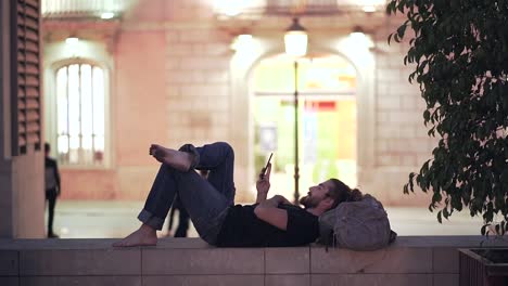 man relaxing with phone in city at night