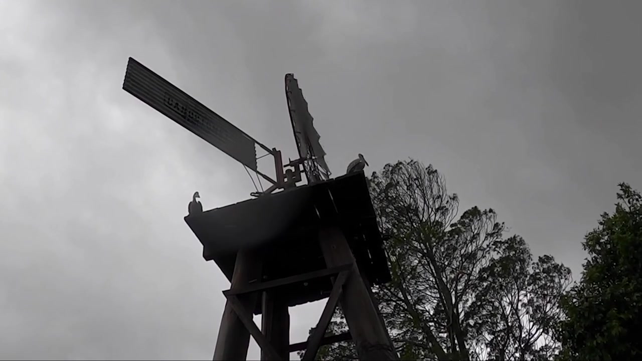 Looking up at a spooky windmill spinning around in the rain on a windy, dark cloudy day.