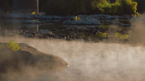 mist rising over the water surface of river during sunrise