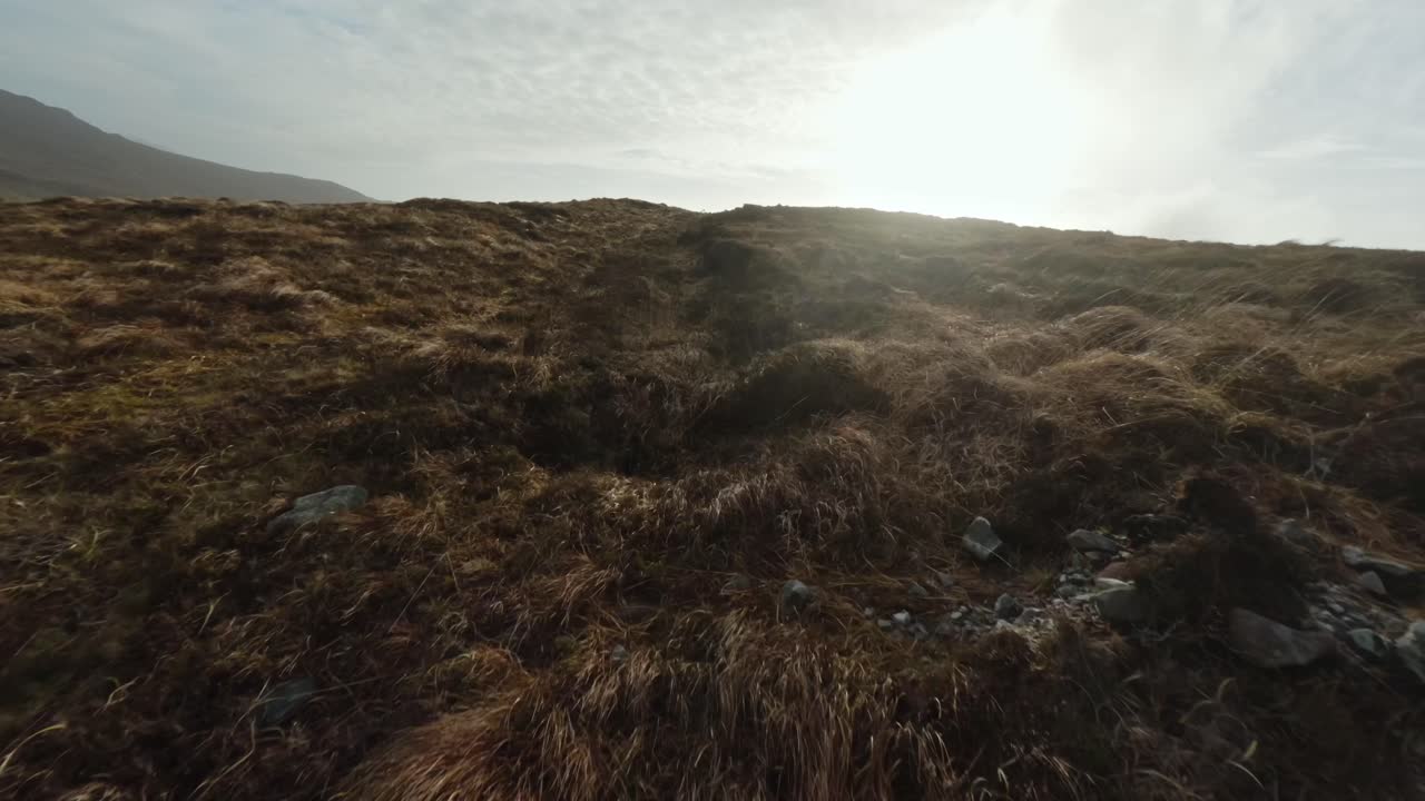 avión no tripulado volando río arriba en una colina en la isla de achill durante la puesta de sol