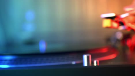 vinyl player turntable. a fragment of a rotating vinyl record, a stylus with a needle close-up. macro. front view. blurred on a background of red and blue lights