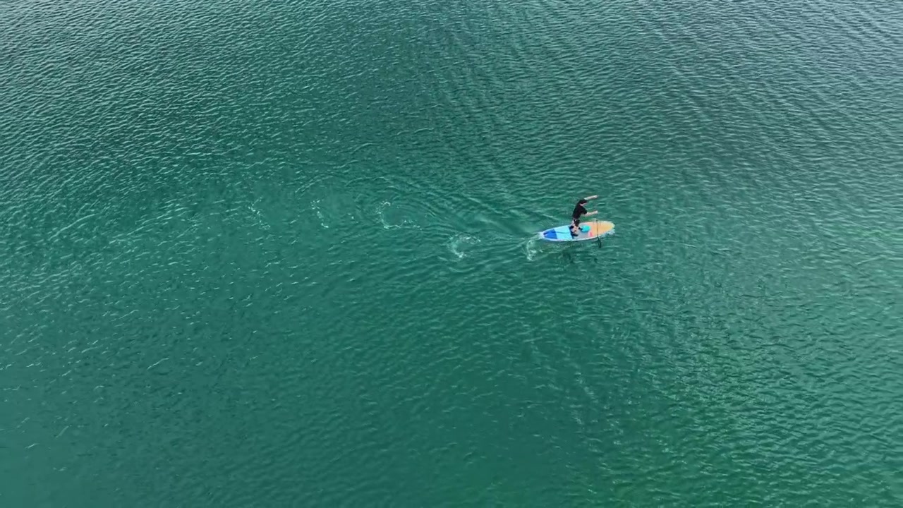 Persona che fa paddleboard su acqua limpida in una baia calma durante le ore diurne.