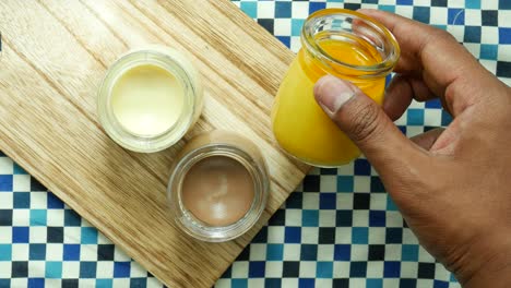 Caramel,-chocolate-and-mango-pudding-in-a-glass-jar-on-pink-background-,